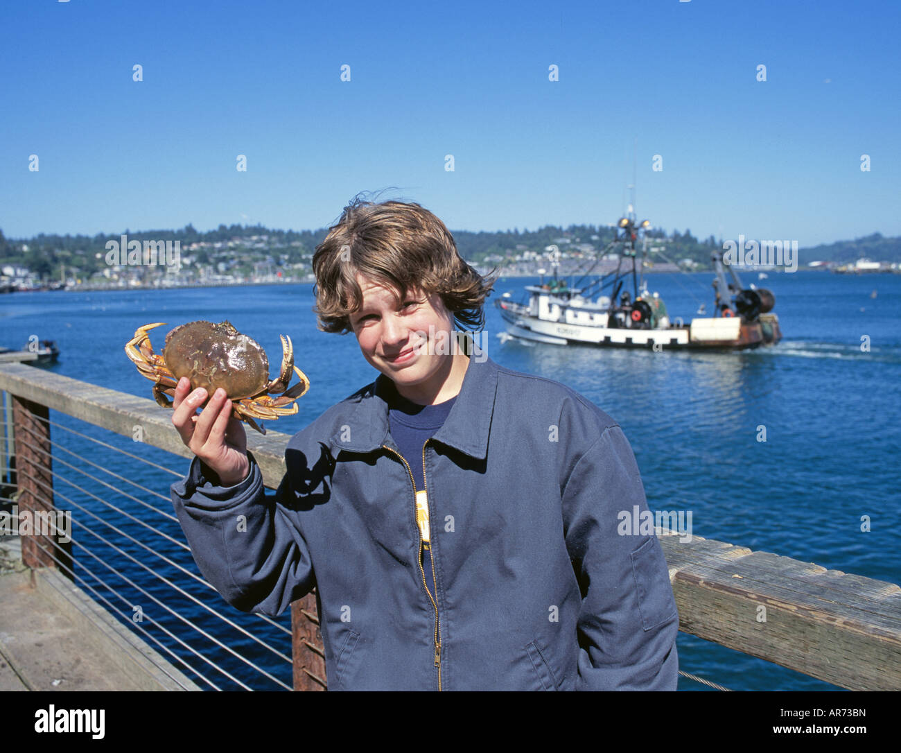 A young boy fishes for dungeness crab off the public wharf in downtown Newport Oregon Stock Photo