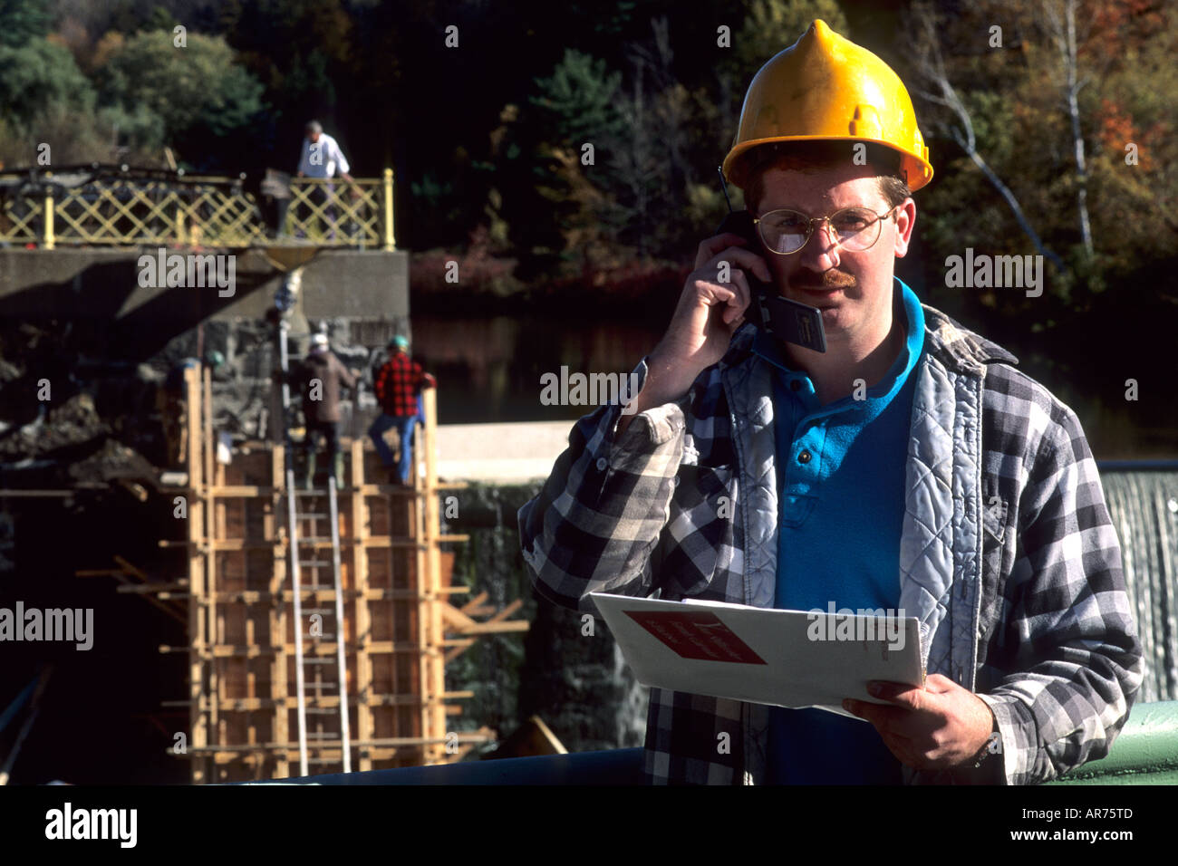 Construction worker on site with cell phone to communicate Stock Photo