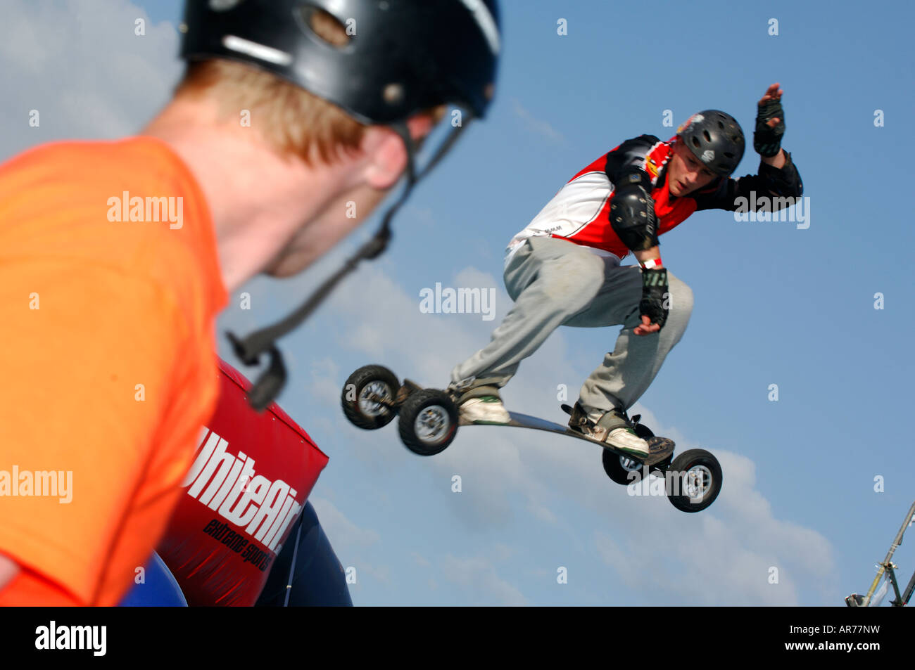 skateboarders mountain boarders wearing protective gear pads and jumping flying through the air doing stunts getting radical Stock Photo