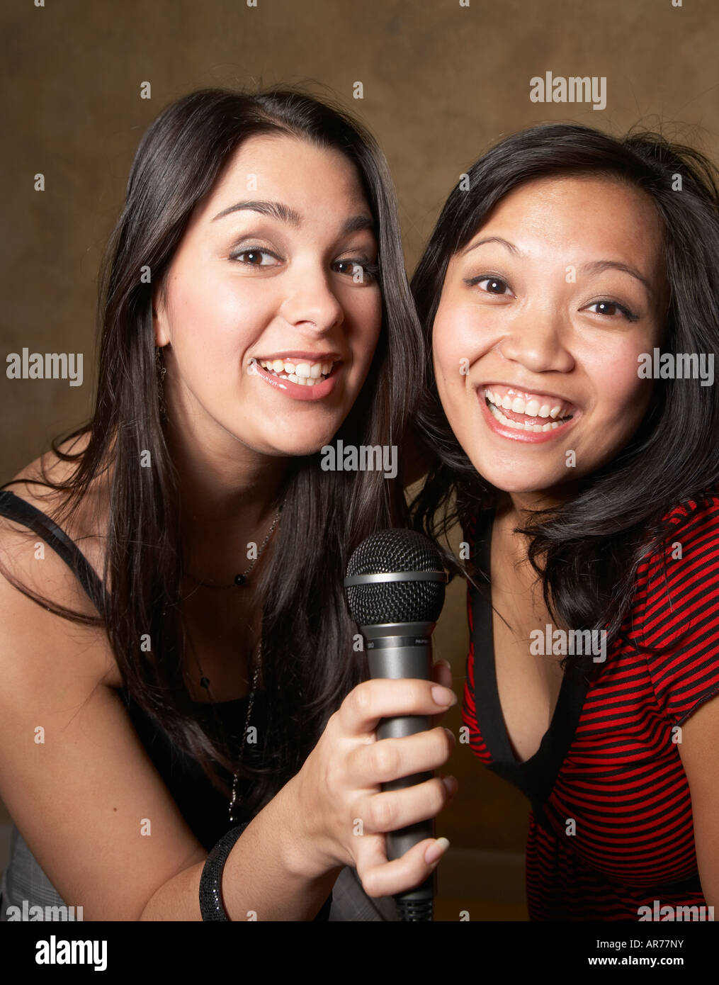 Multi-ethnic friends singing with microphone Stock Photo - Alamy