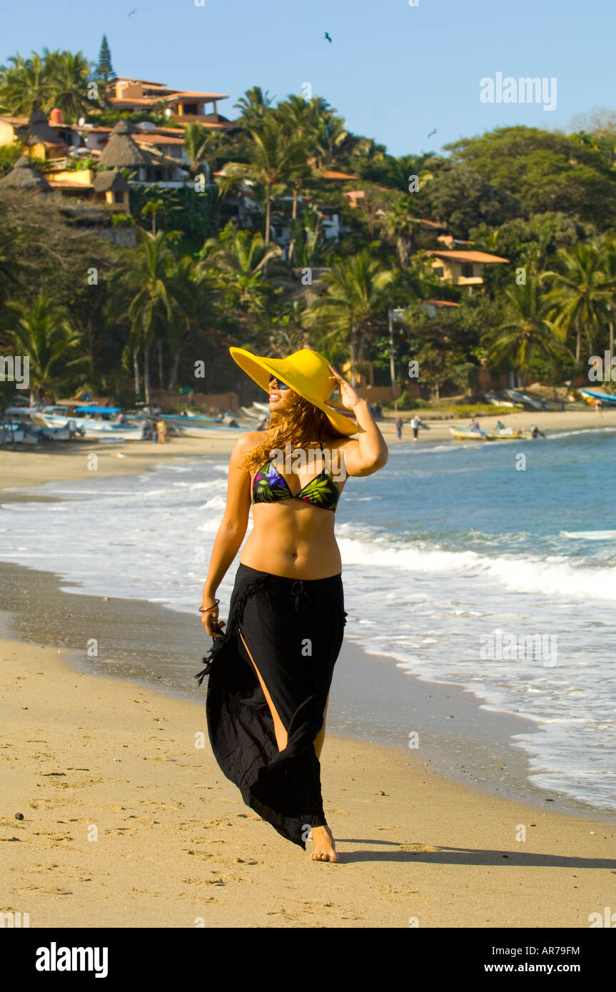 Mexico Nayarit Village of Sayulita near Puerto Vallarta on the Pacific Ocean  woman in yellow hat enjoying a walk on the beach Stock Photo