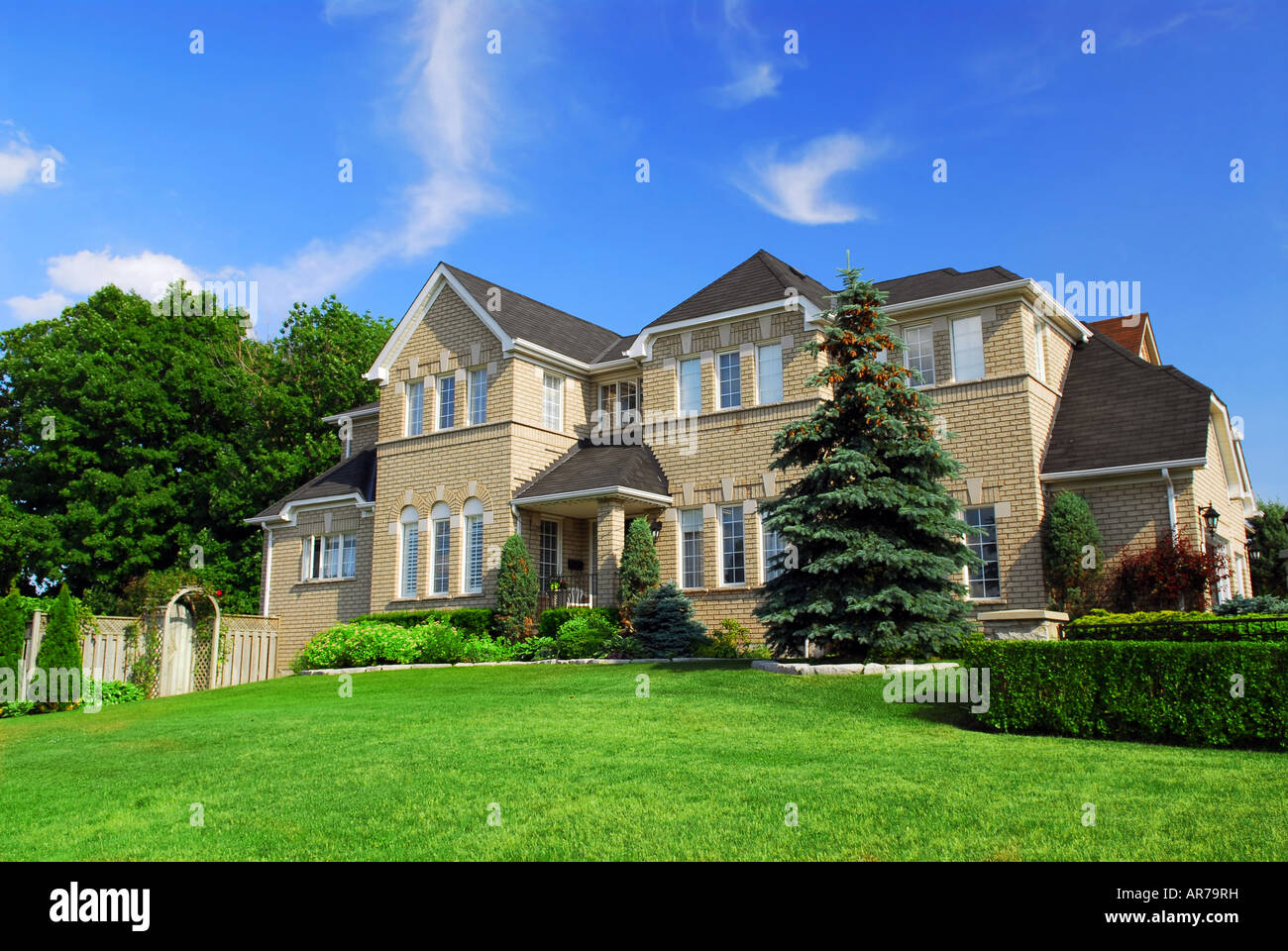 Large upscale residential home with bright green lawn and blue sky Stock Photo