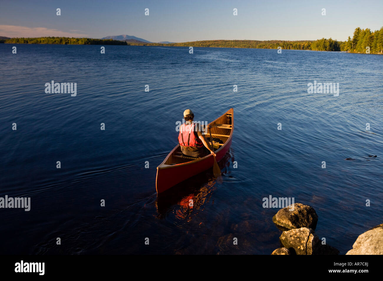 A man paddles his canoe on Seboeis Lake near Millinocket, Maine. Mount