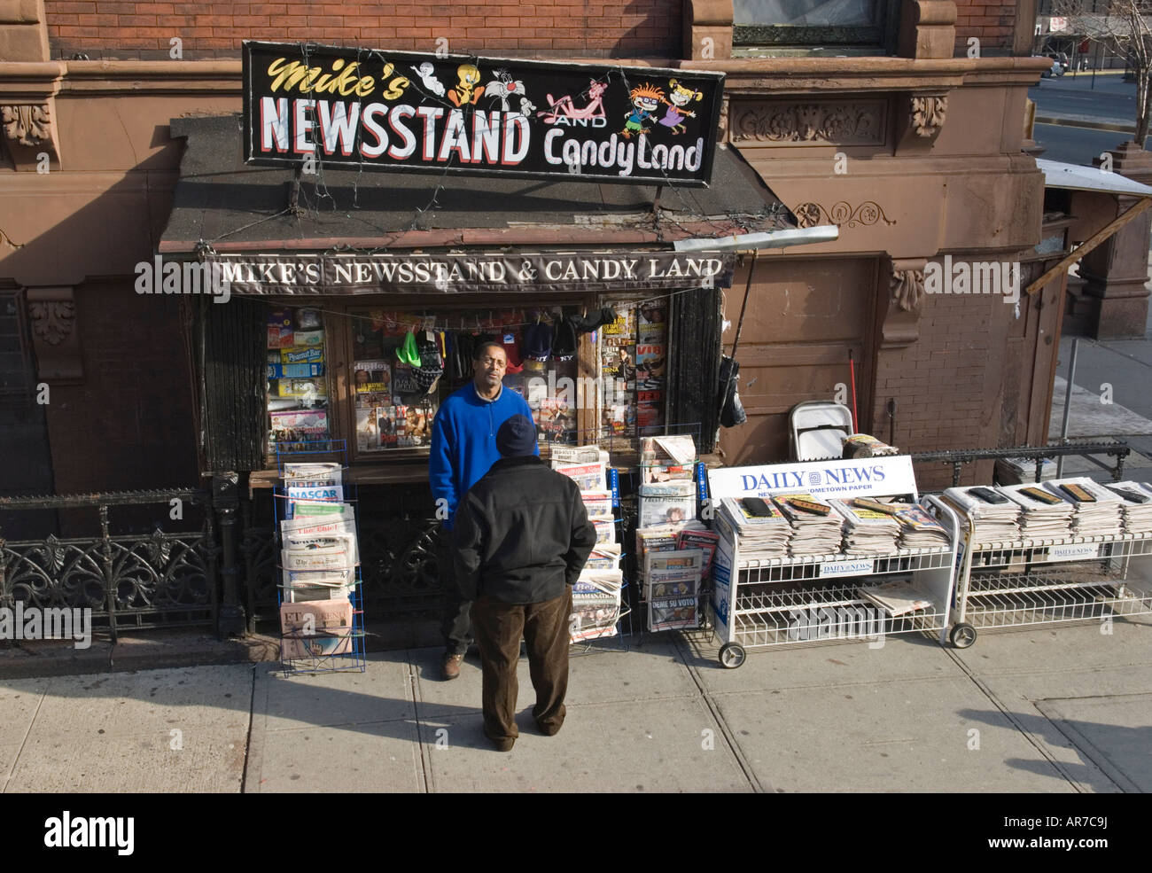 Two men talking at a newsstand in Harlem, New York CIty ...