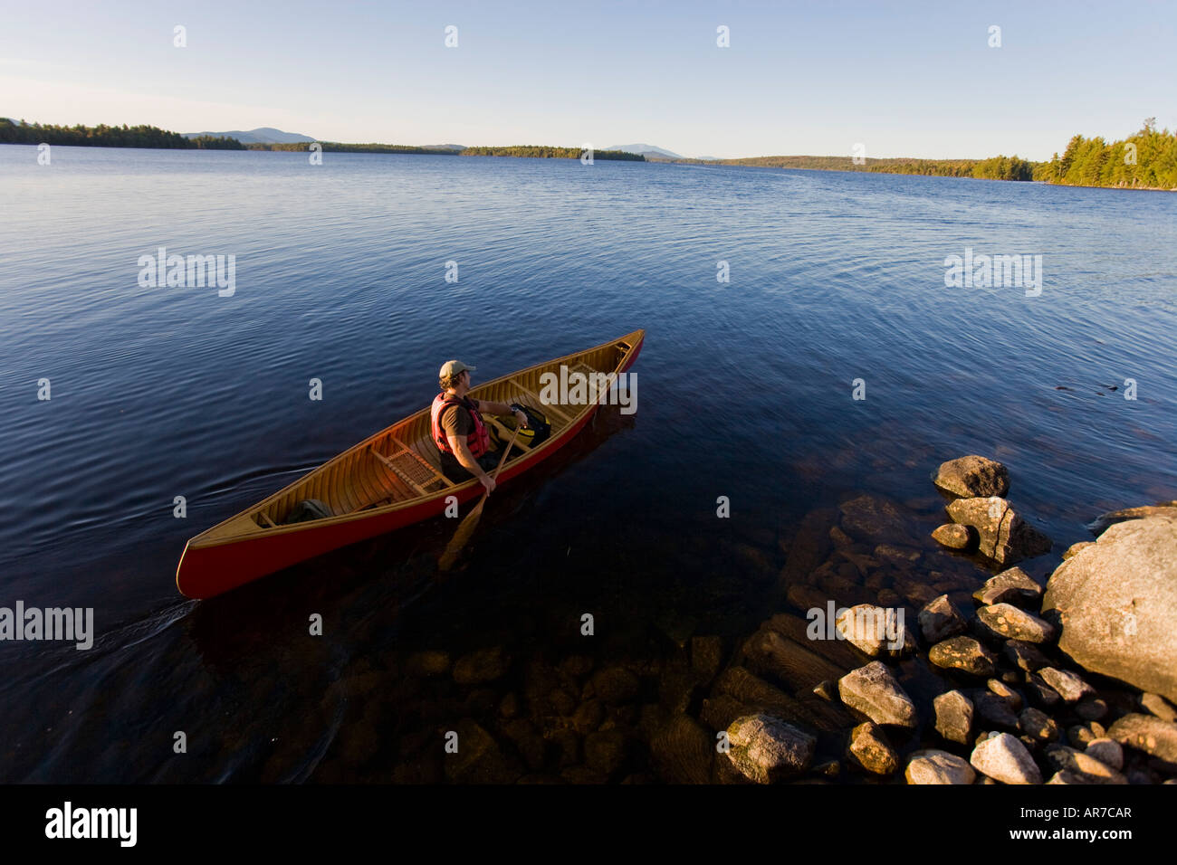 A man paddles his canoe on Seboeis Lake near Millinocket, Maine. Mount