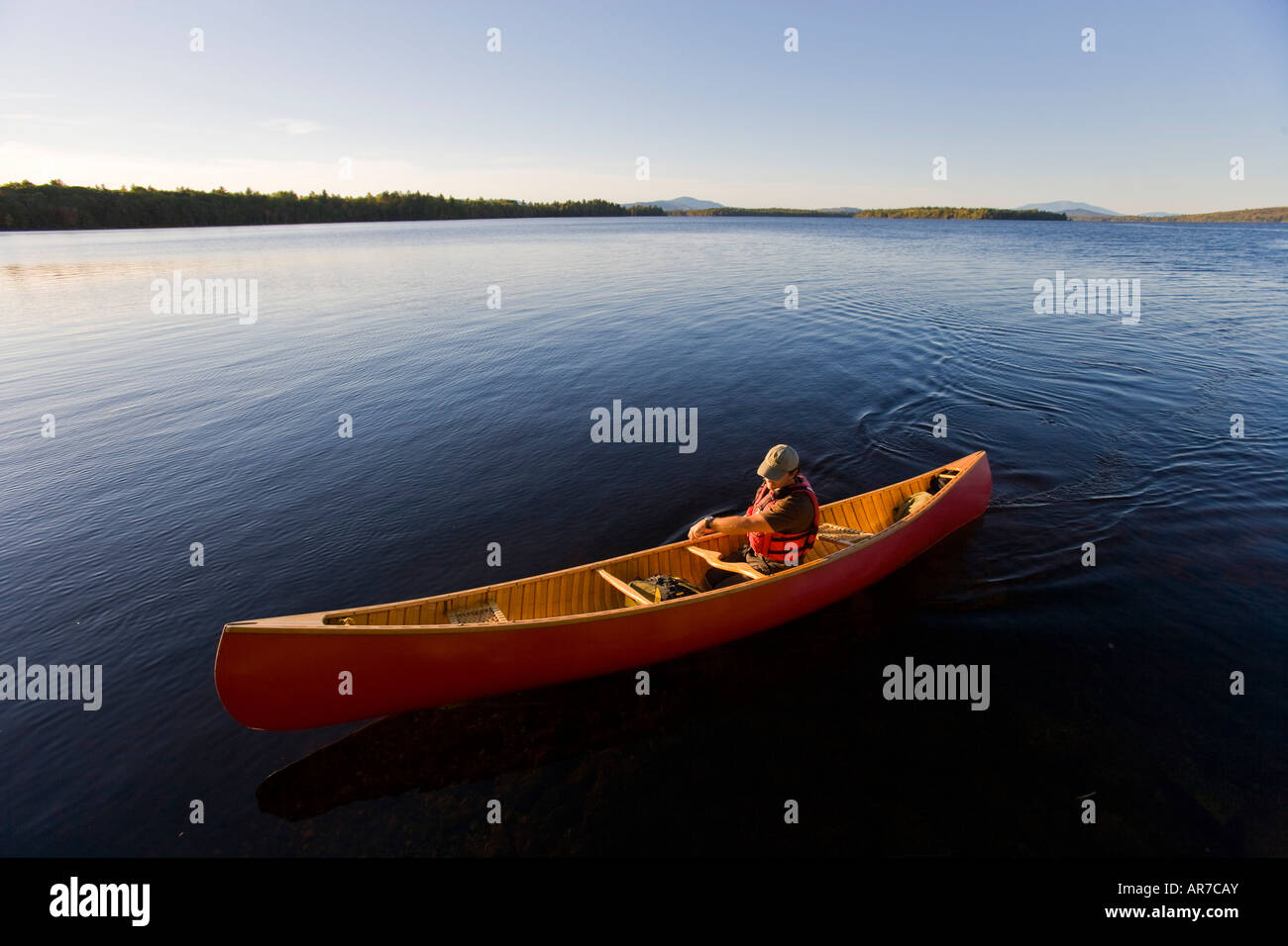 A man paddles his canoe on Seboeis Lake near Millinocket, Maine. Mount