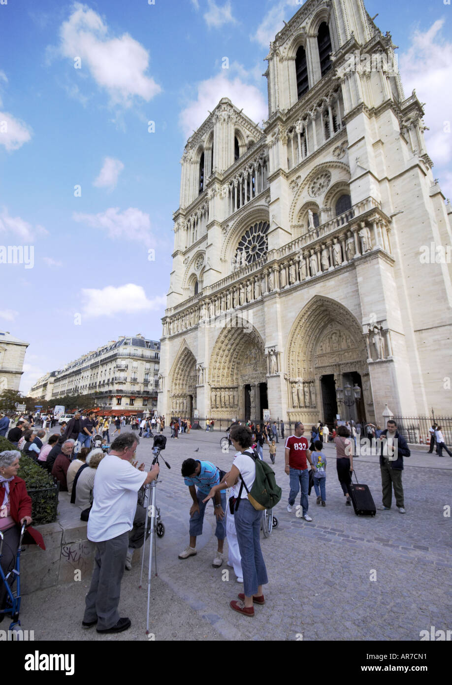 tourists with cameras and two gothic towers of Notre Dame Cathedral in