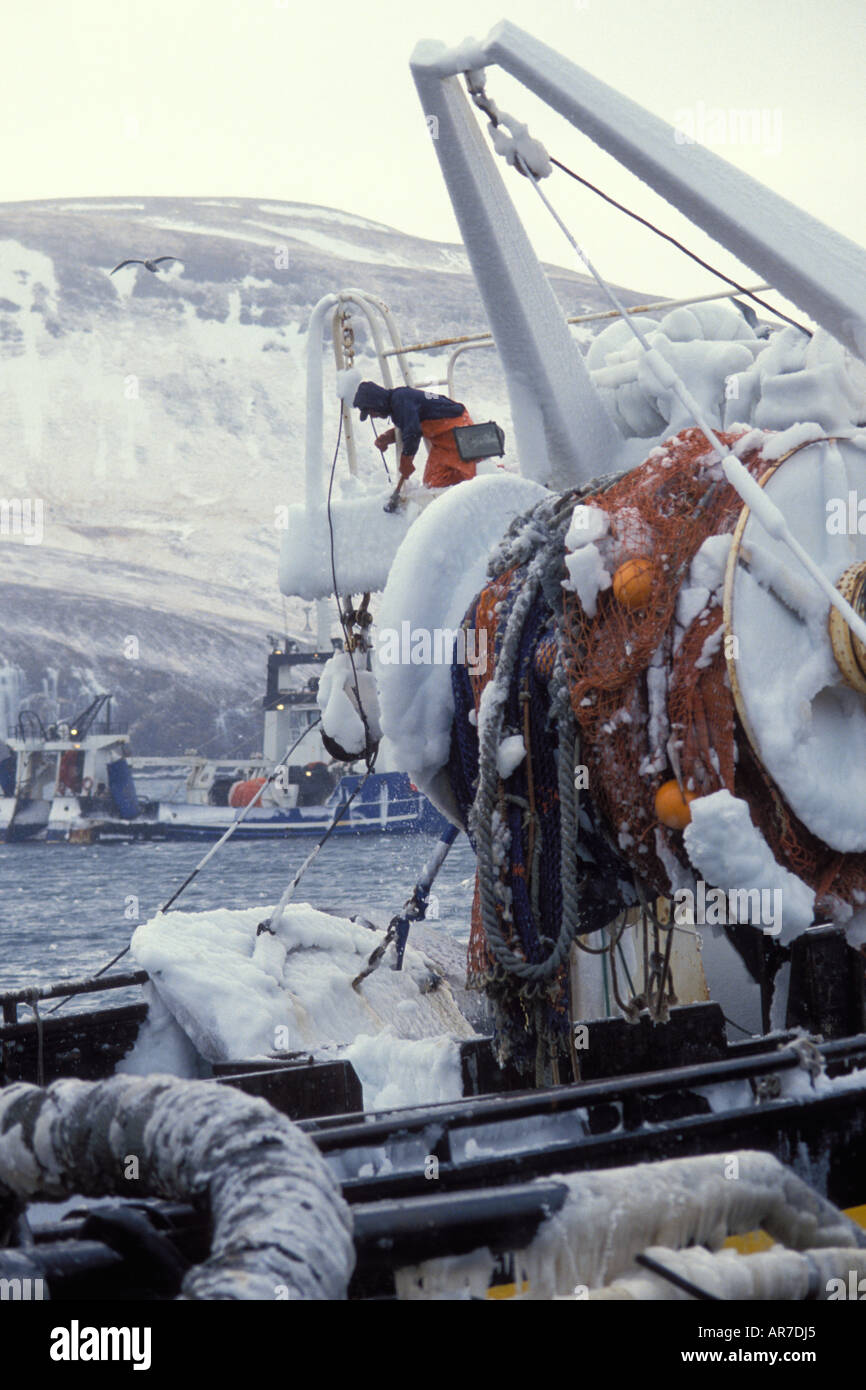 crew on a commercial dragger fishing vessel break off accumulated ice Akutan Alaska Stock Photo