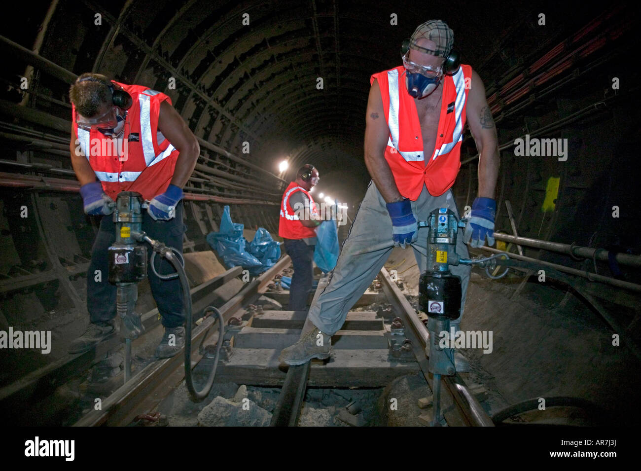 Underground operatives using compressed air jackhammers in a rail Stock