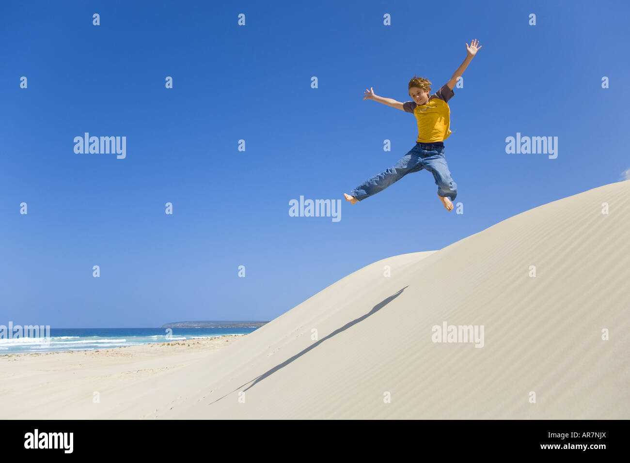 Boy jumping in sand dune Stock Photo Alamy