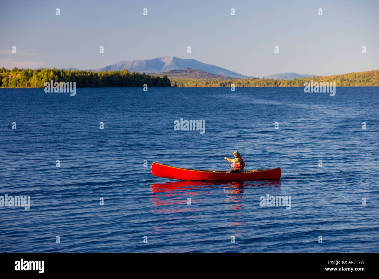 A man paddles his canoe on Seboeis Lake near Millinocket, Maine. Mount