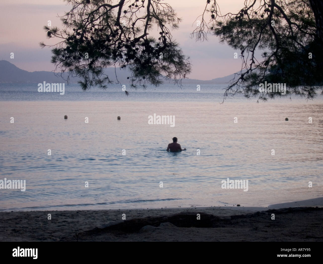Swimmer off the beach at dusk Stock Photo