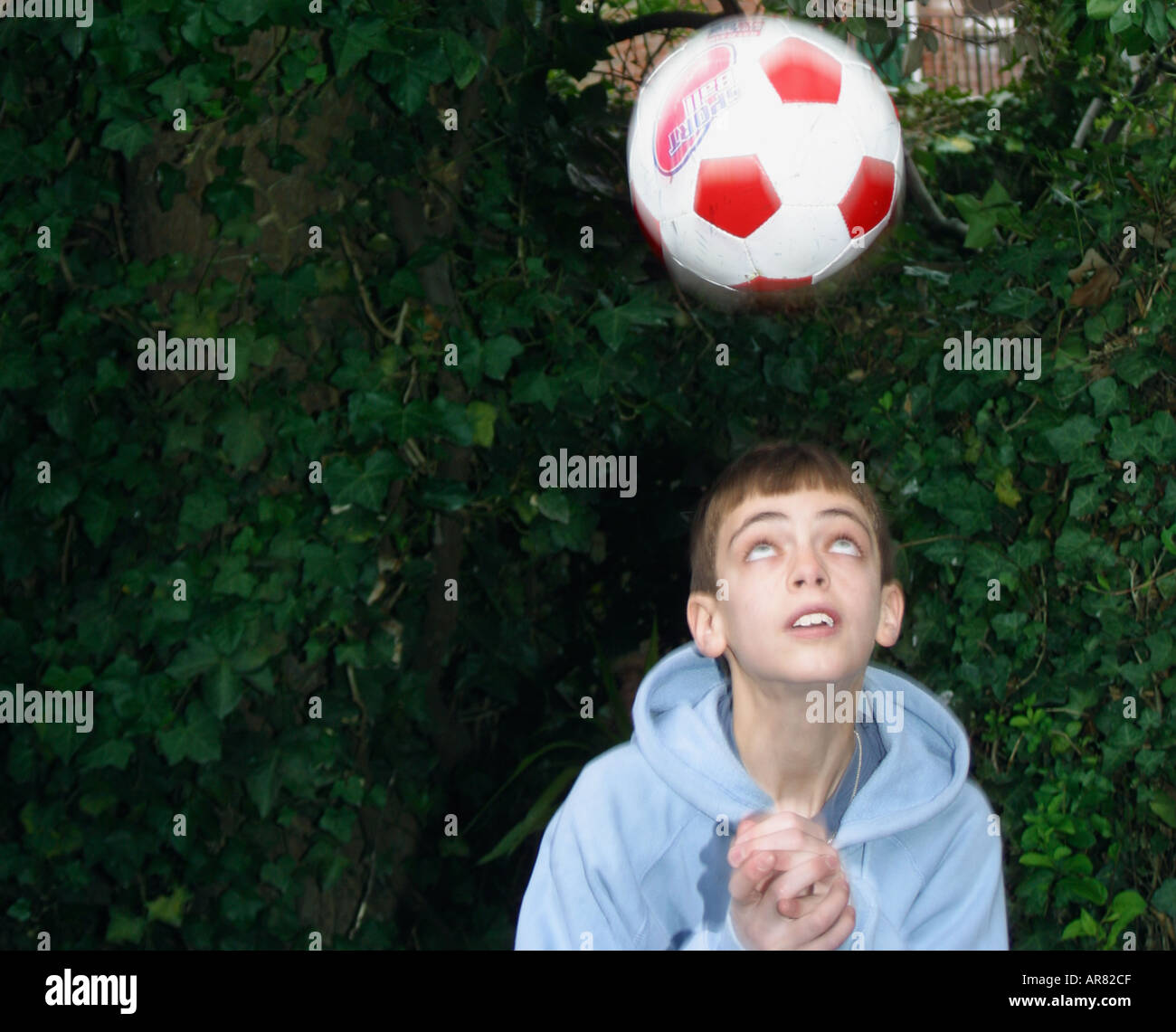 Boy heading football outdoors Stock Photo