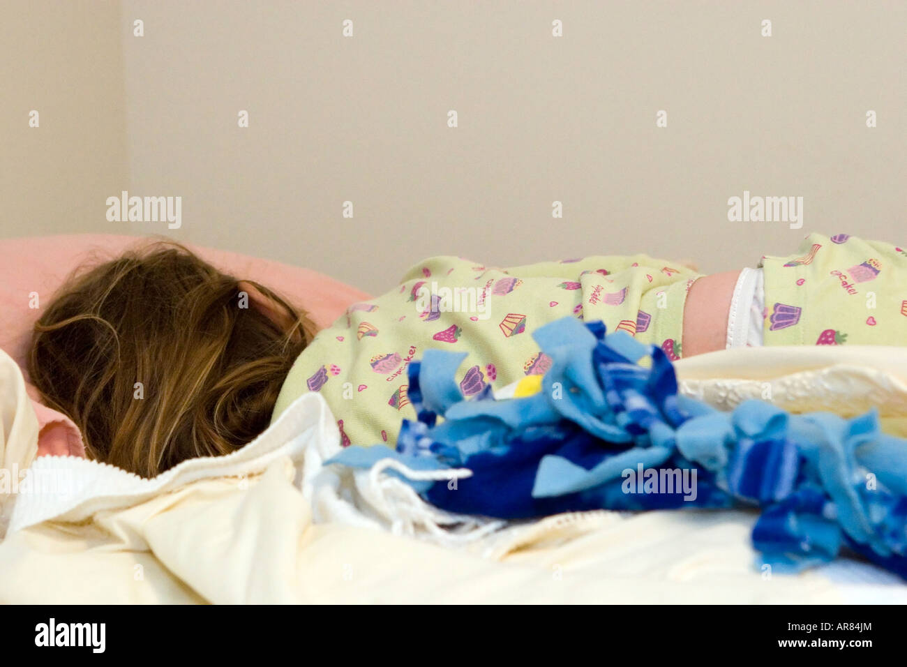Young girl age 4 fast asleep on bed with assorted blankets. The day