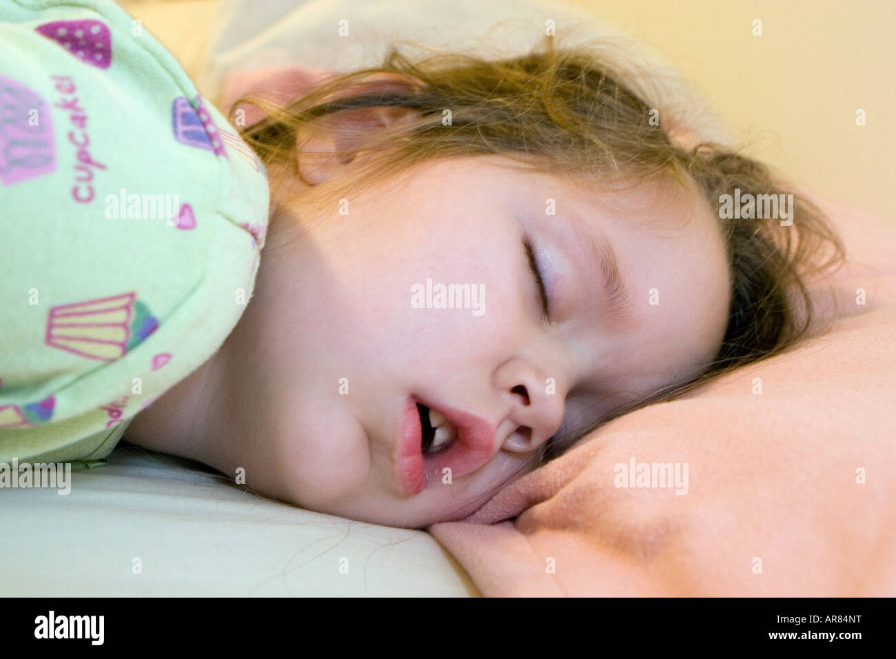 Young girl age 4 fast asleep with mouth wide open on pillow. The day after Christmas requires extra sleep Stock Photo