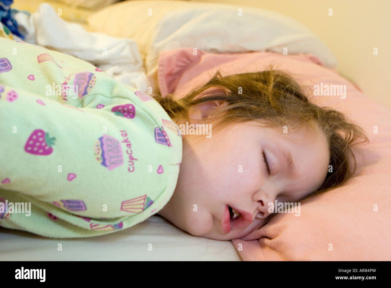 Young girl age 4 fast asleep with mouth wide open on pillow. The day after Christmas requires extra sleep Stock Photo