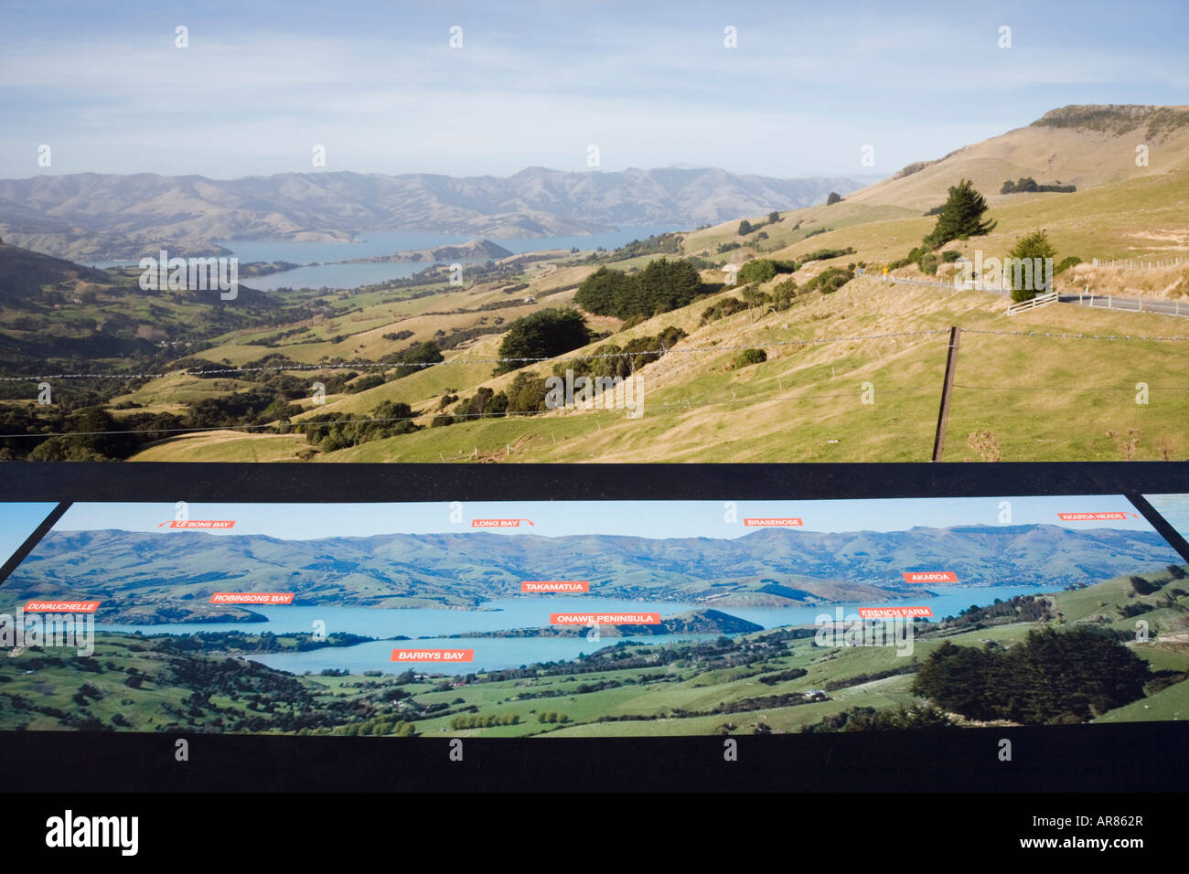 Pictorial tourist sign and view down to Barrys Bay in 'Banks Peninsula' from roadside Hilltop viewpoint South Island New Zealand Stock Photo