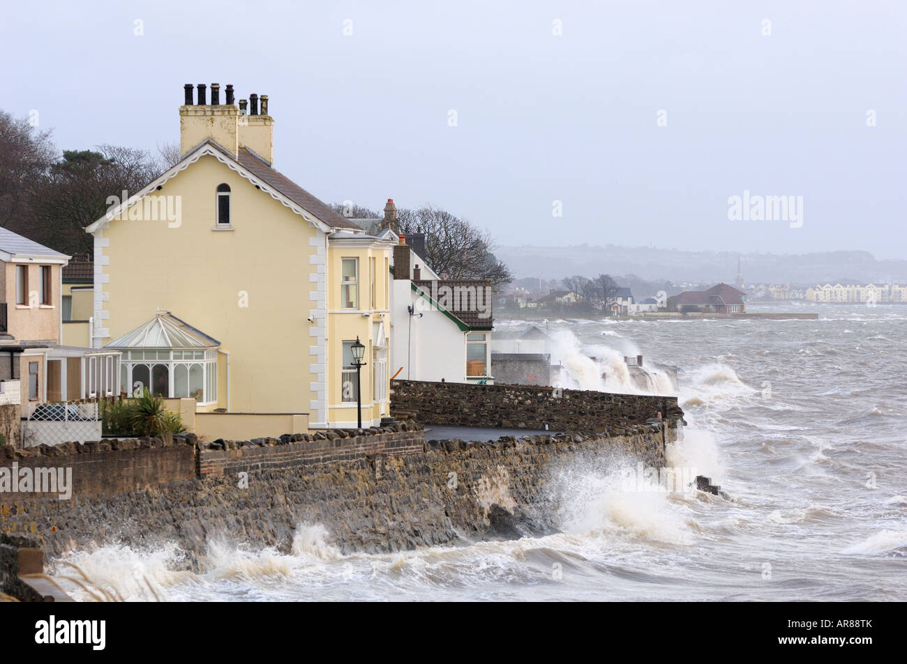 Waves break over a wall in belfast lough during a winter storm Stock Photo