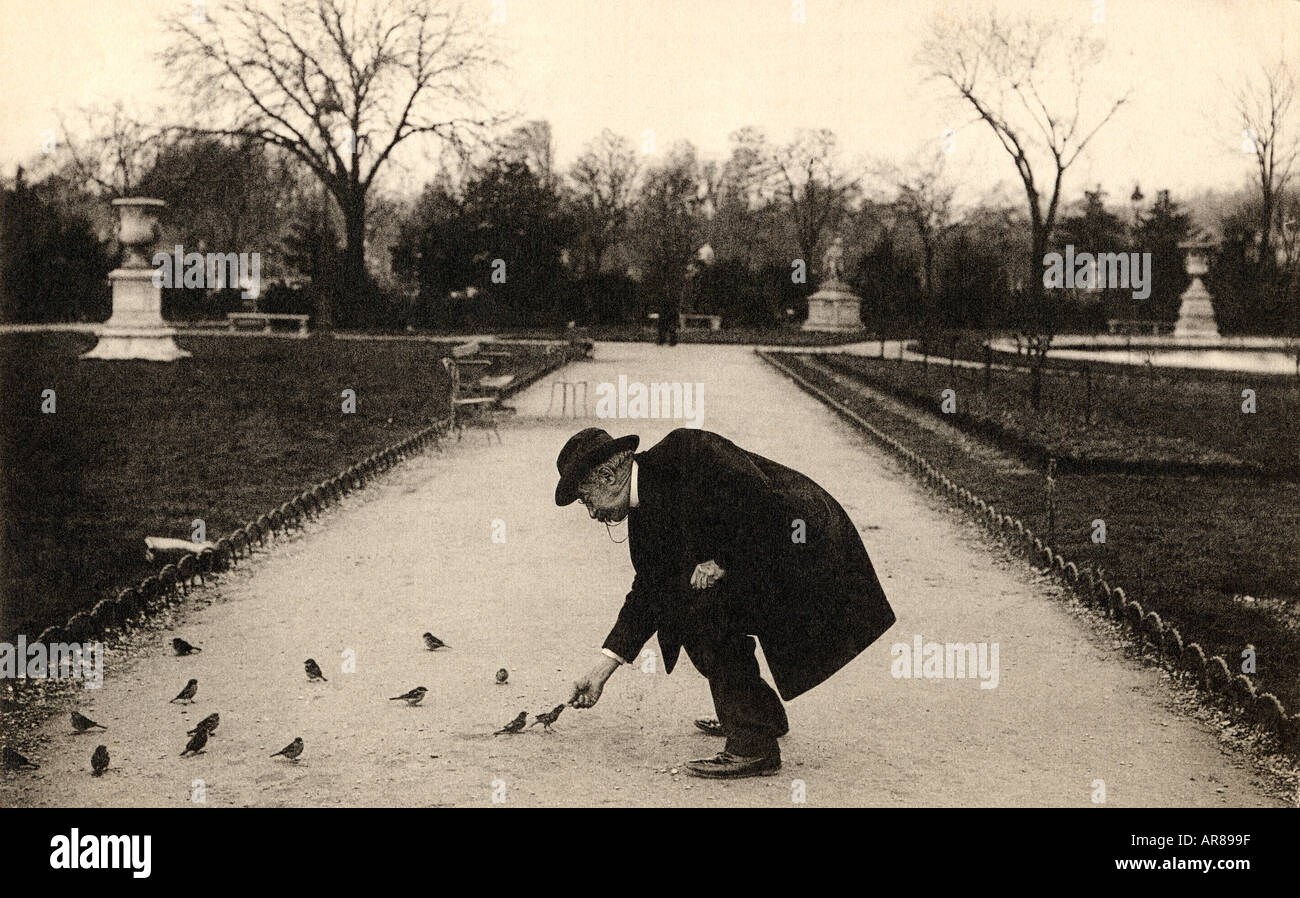 Vintage Image of Man Bent Over Feeding Birds in Park Stock Photo