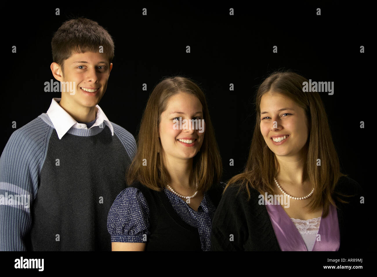 Two sisters and their brother smiling Stock Photo - Alamy
