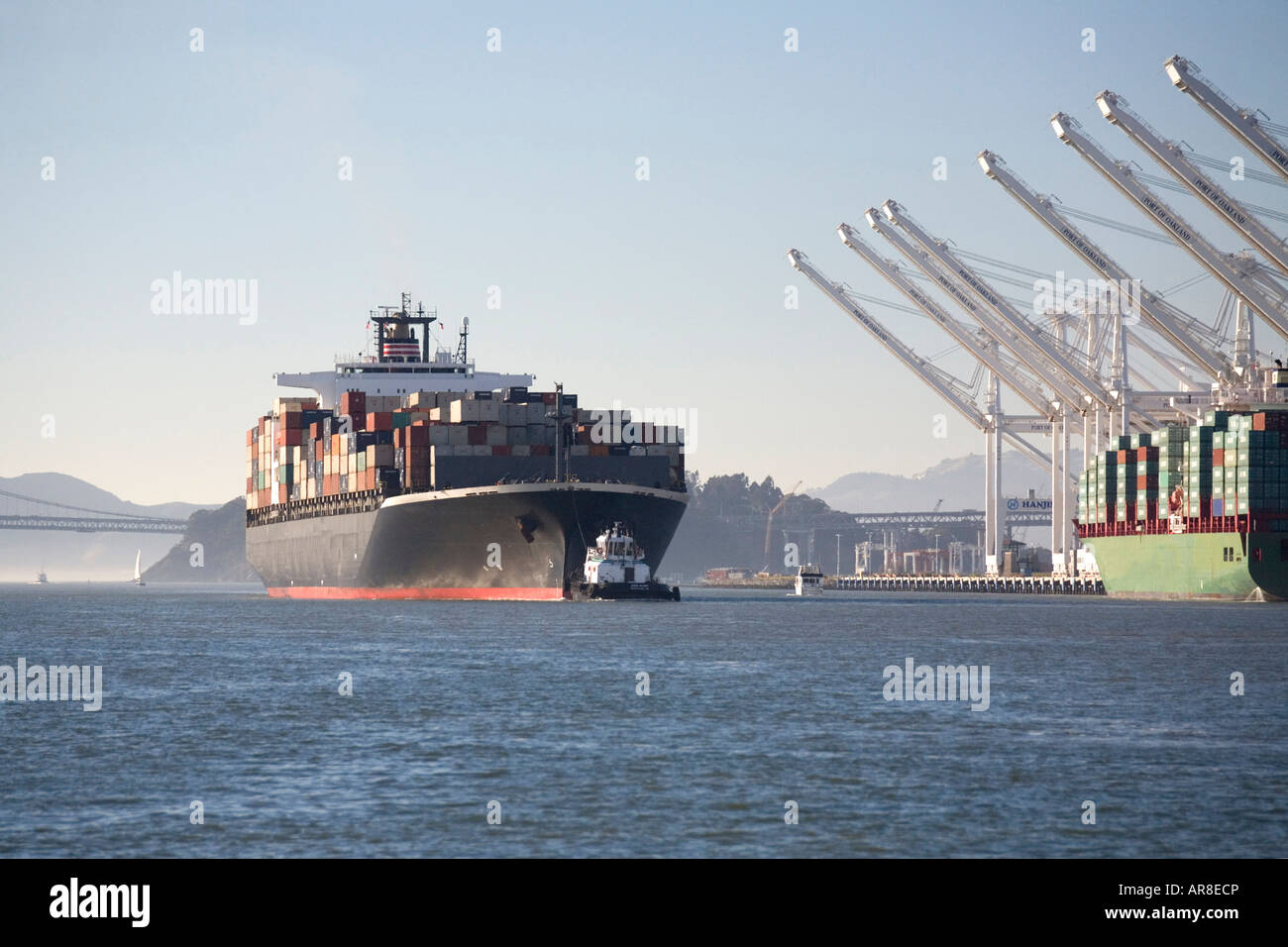 Wider view of ship entering Oakland with cranes ready to offload the cargo. Stock Photo