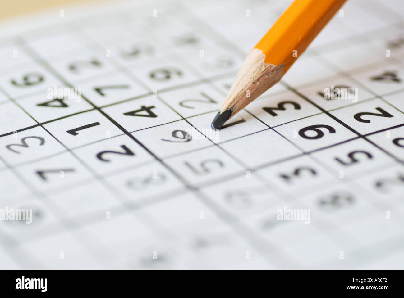 Completing Sudoku puzzle with pencil Stock Photo