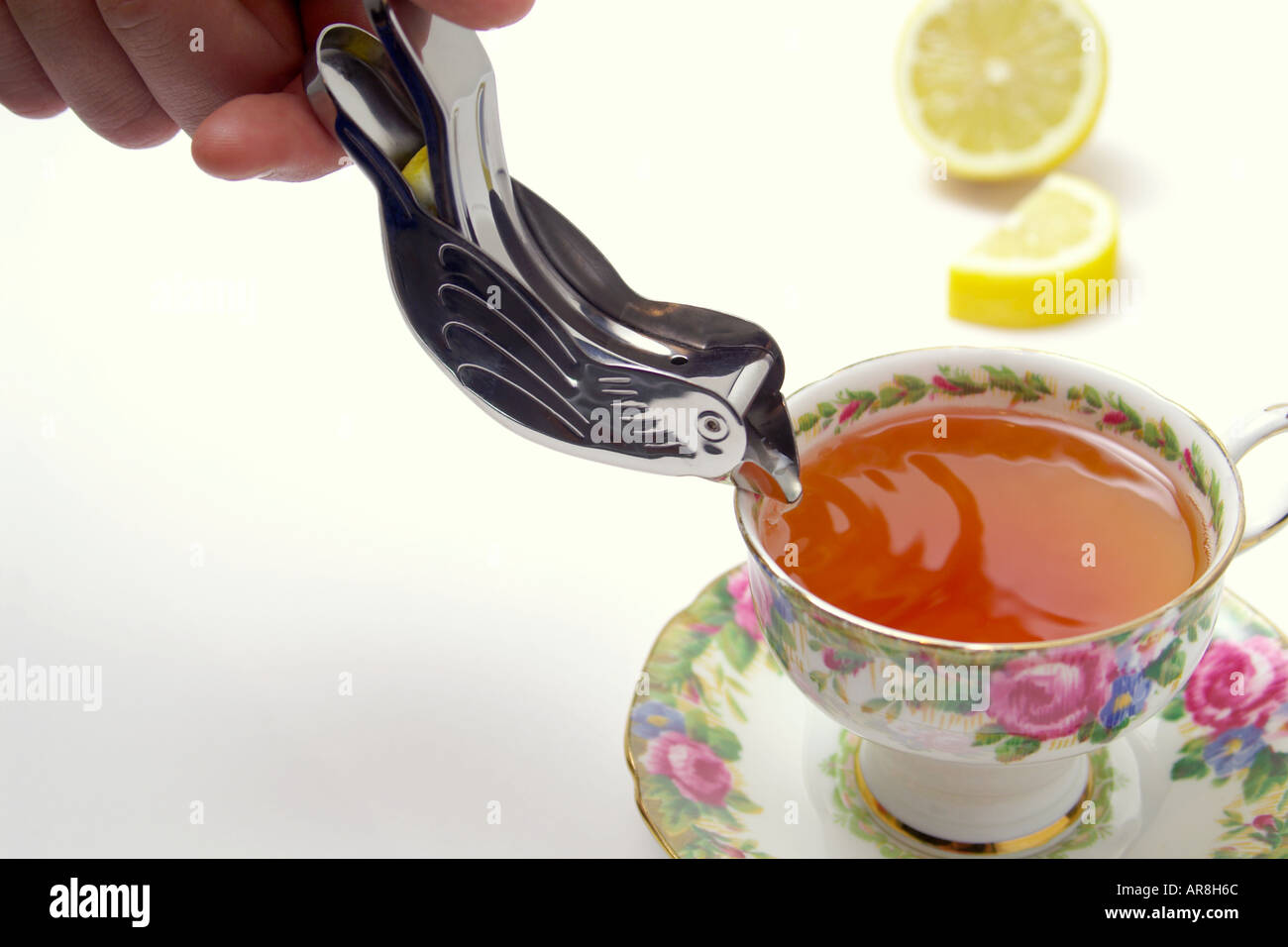 adding lemon juice to tea with lemon slice squeezing utensil Stock