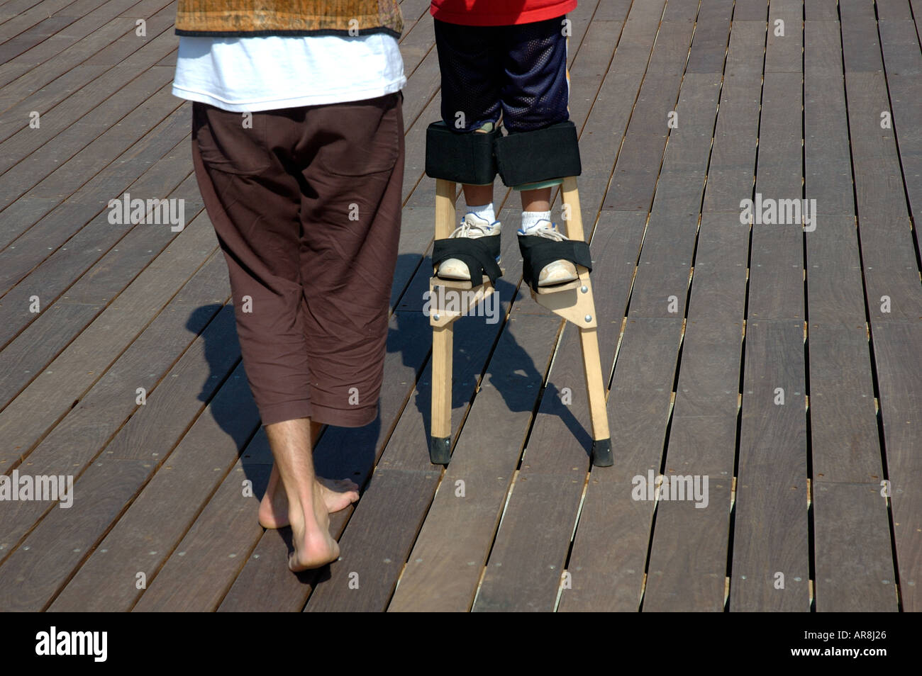 Young boy walking on stilts with his mother Stock Photo