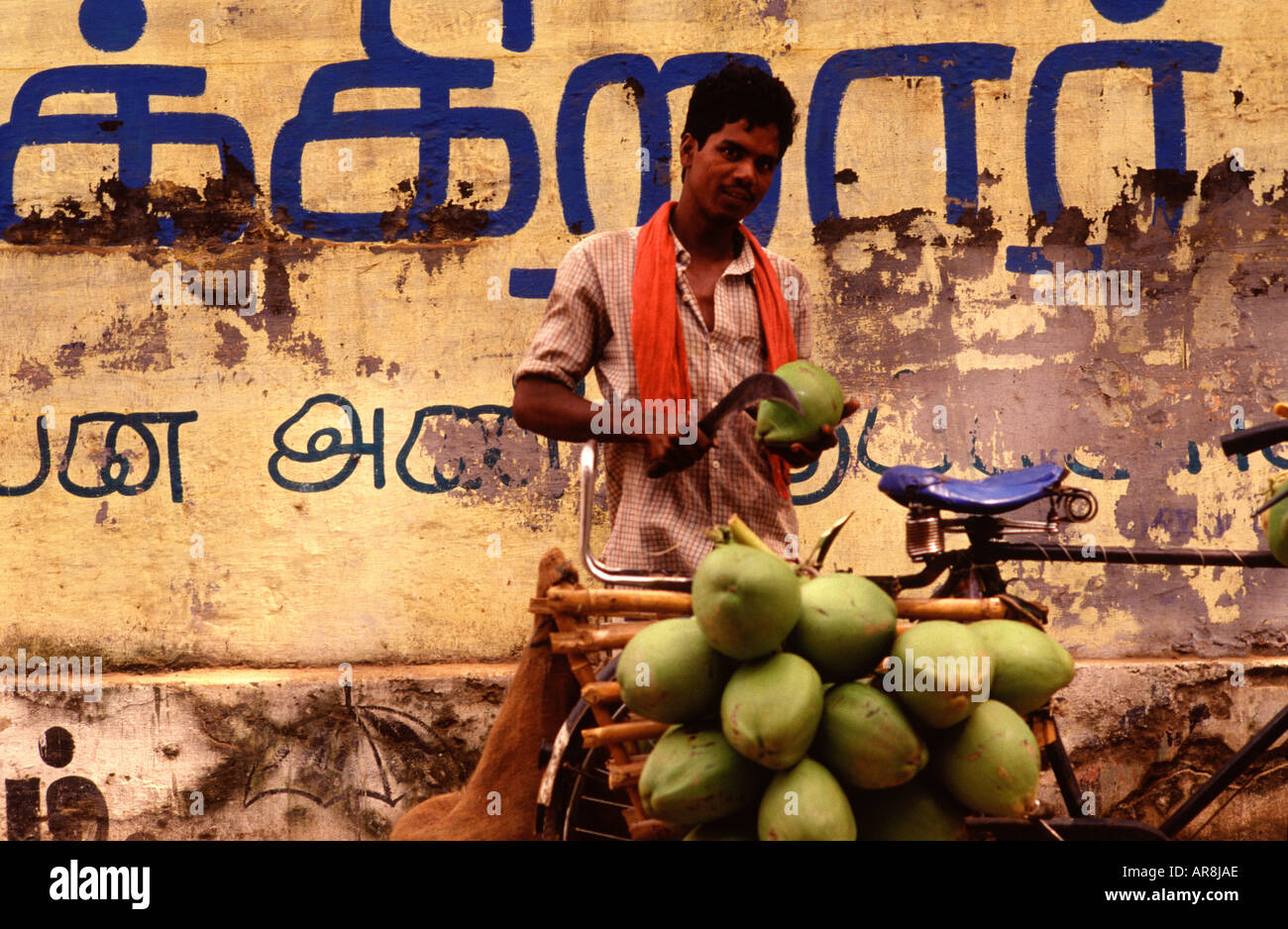 An Indian man cuts a green coconut with a sharp chopper for coconut water juice in Tamil Nadu
