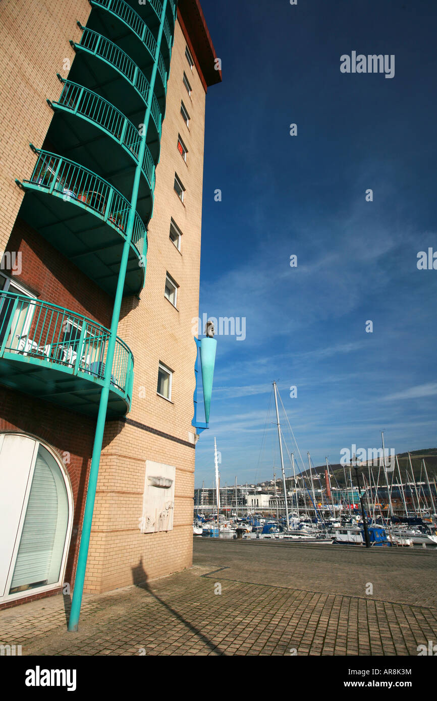 Luxury harbour side apartment building Swansea marina with millennium sail bridge and moored boats in background South Wales UK Stock Photo