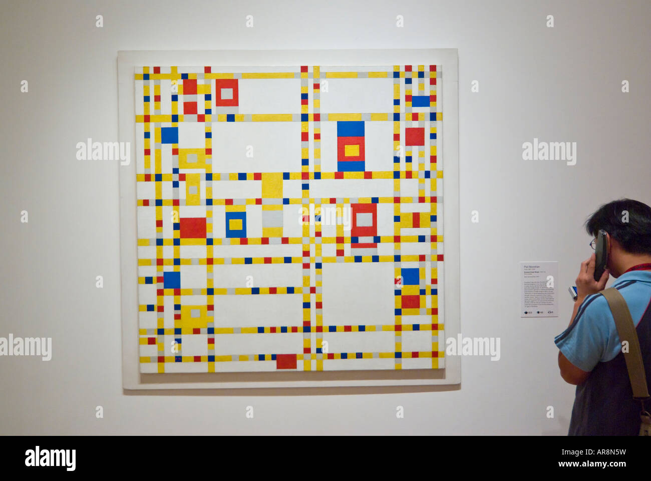 spectator listening to audio guide in front of painting by Mondrian, Broadway Boogie Woogie, The Museum of Modern Art, New York Stock Photo