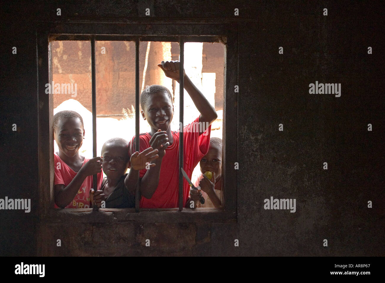 Ghanaian children peeking through barred window Stock Photo