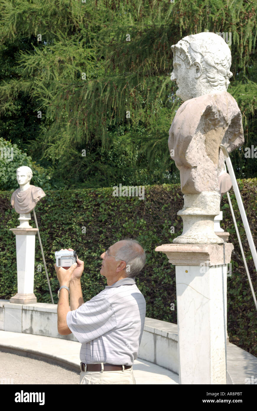An older tourist takes a picture among statuary on the terrace at Schloss Sanssouci, Potsdam, Germany. Stock Photo