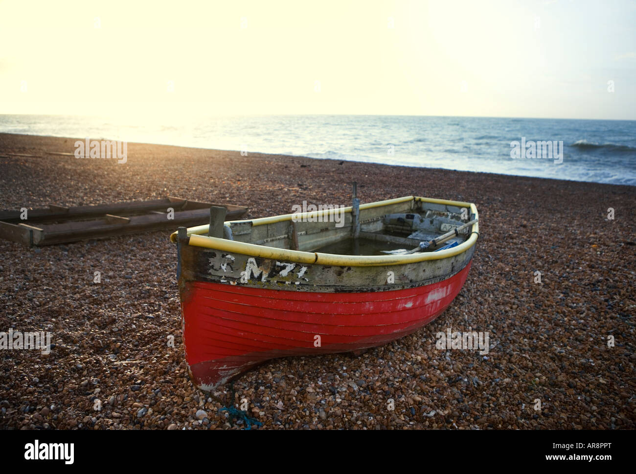 Red fishing boat on a shingle beach in the UK Stock Photo