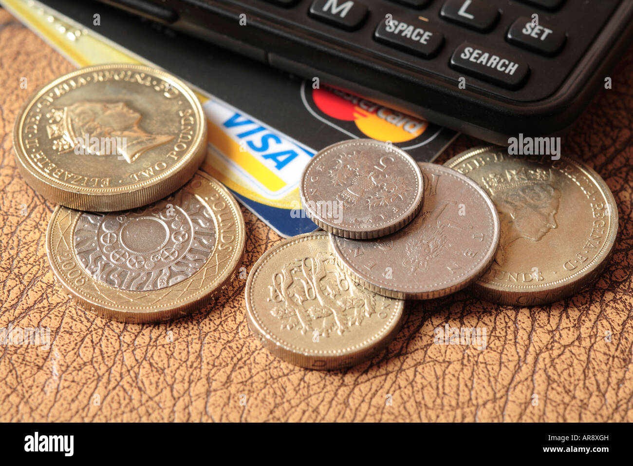 Pile of pound and two pound coins and small change, credit cards and calculator. Stock Photo