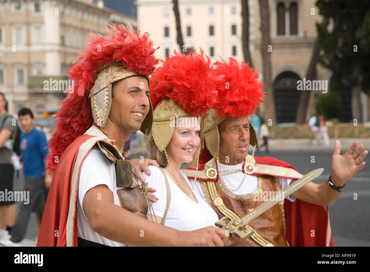 Roman soldiers pose with a tourist outside the colosseum in Rome Stock Photo