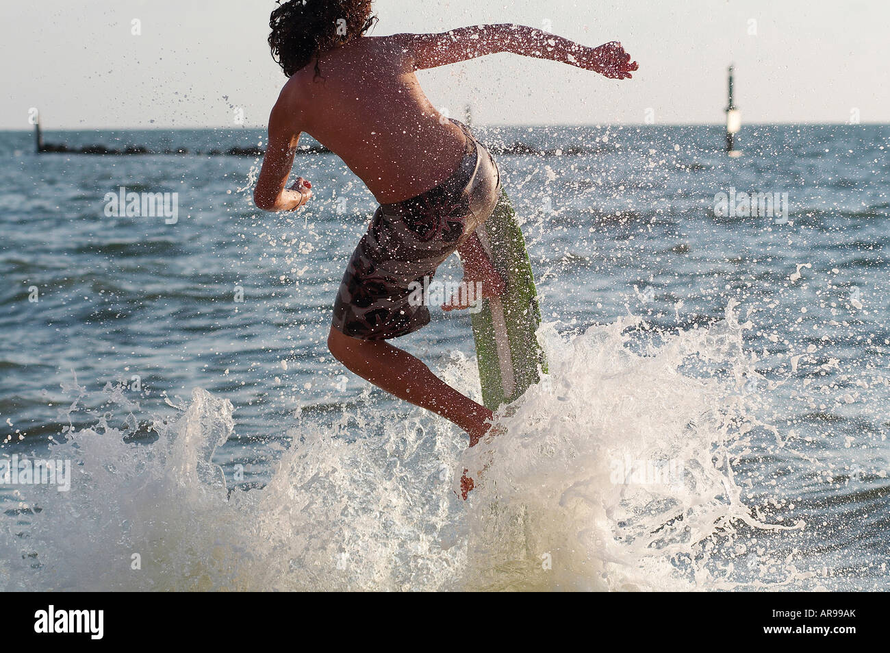 Teenage boy on skimboard jumping and splashing in the waves on a beach in Florida Stock Photo