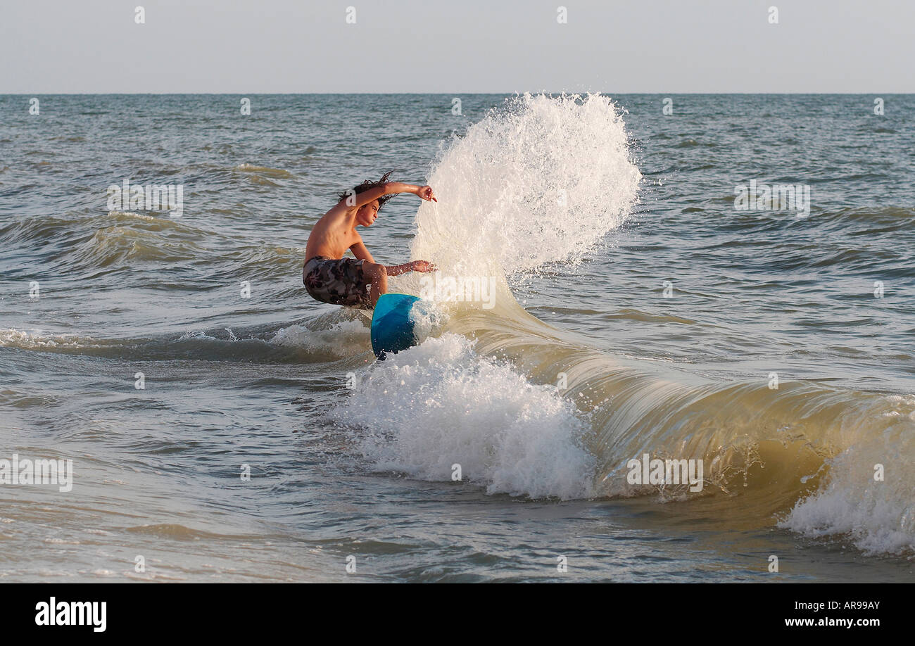 Teenage boy on skimboard jumping and splashing in the waves on a beach in Florida Stock Photo