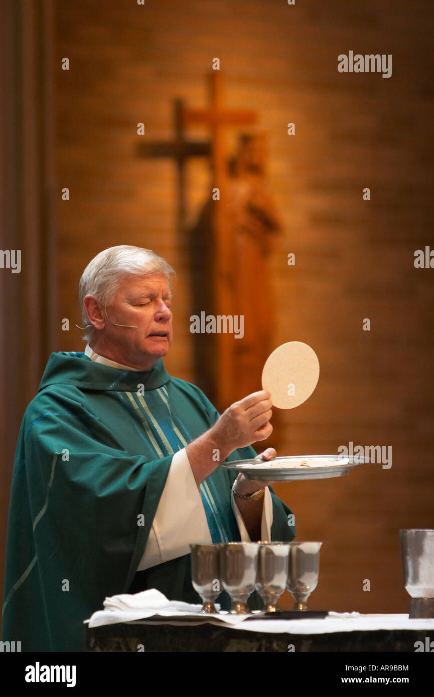 A Catholic Priest holding the Host performing the Eucharist Celebration during Mass Stock Photo