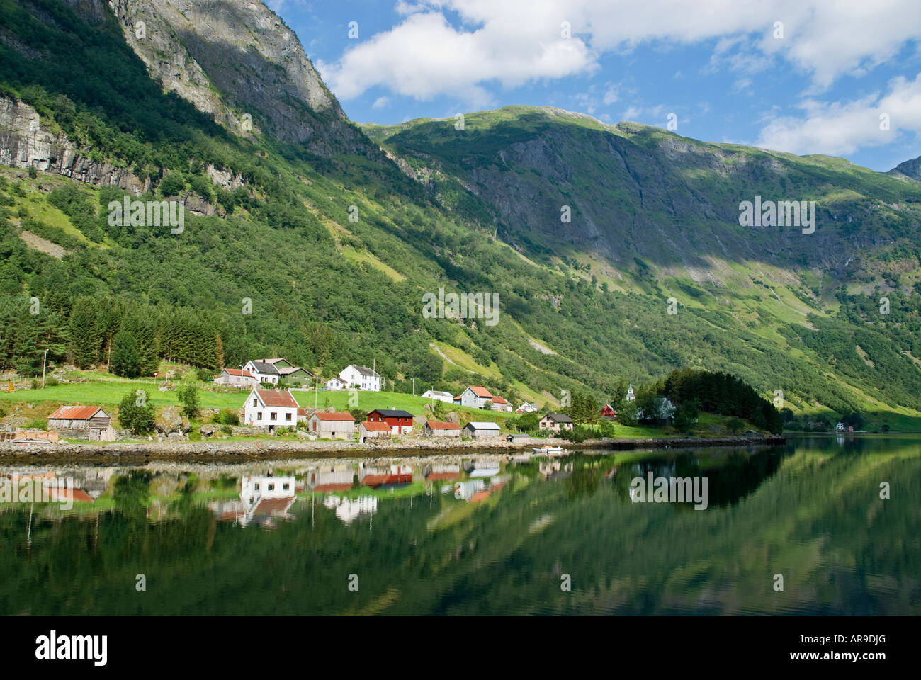 reflection of buildings in water on the shore of Naeroyfjord, near Gudvangen, Norway Stock Photo