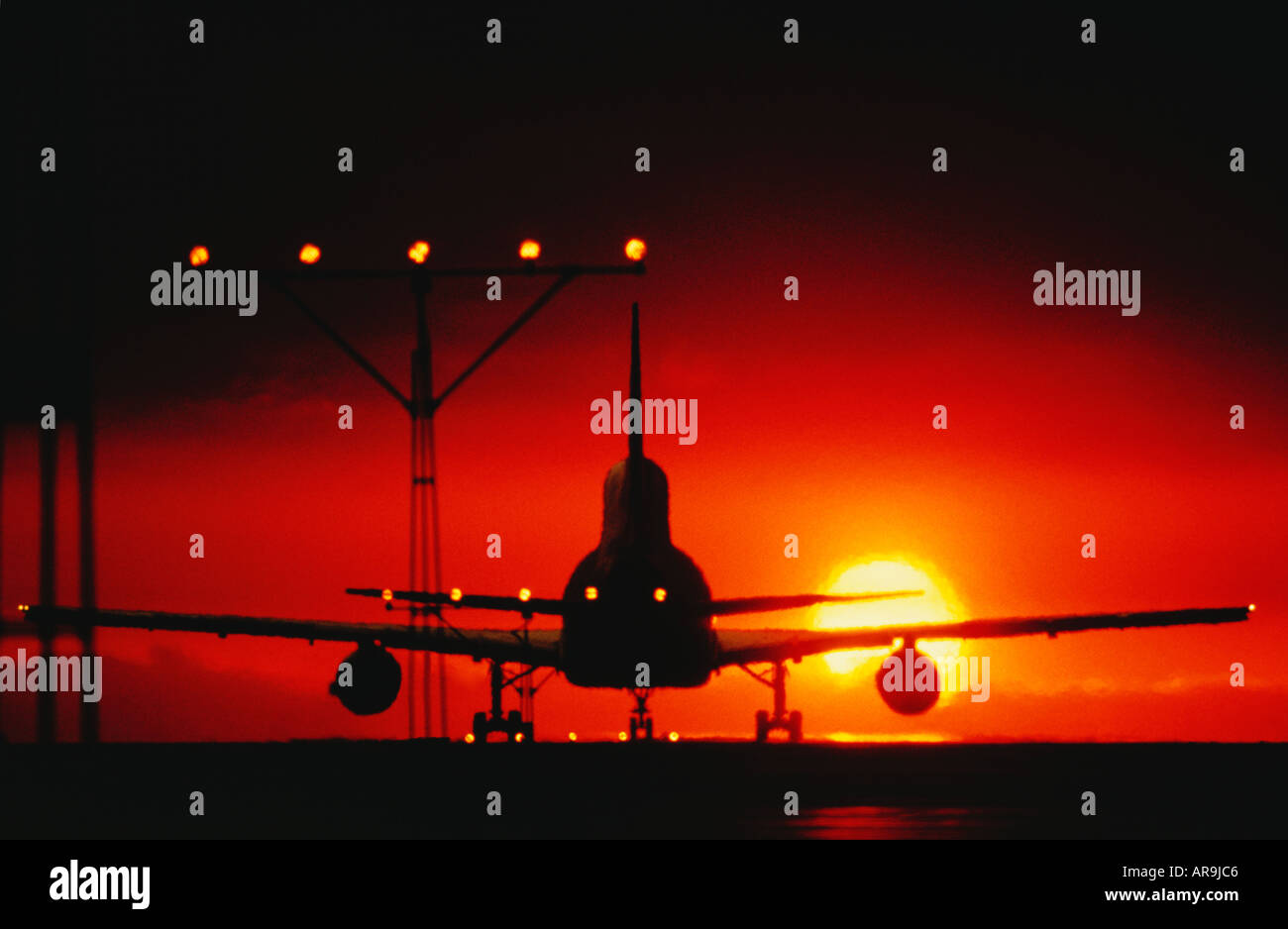 jumbo jet on the runway for take off landing approach lights heading into an golden orange sky at sunset sunrise dusk night show Stock Photo