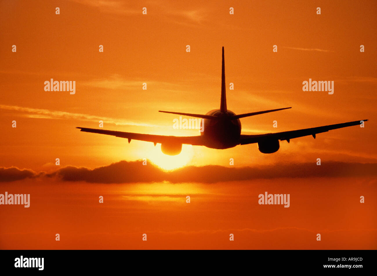 Boeing 737 jet at cruising altitude in the air take off golden orange sky at sunset sunrise dusk Stock Photo