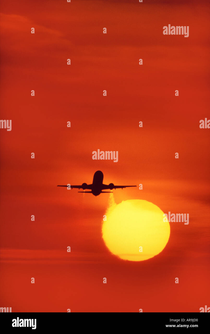 Boeing 737 jet in the air take off  heading into an golden orange sky at sunset sunrise dusk showing jet thrust exhaust Stock Photo