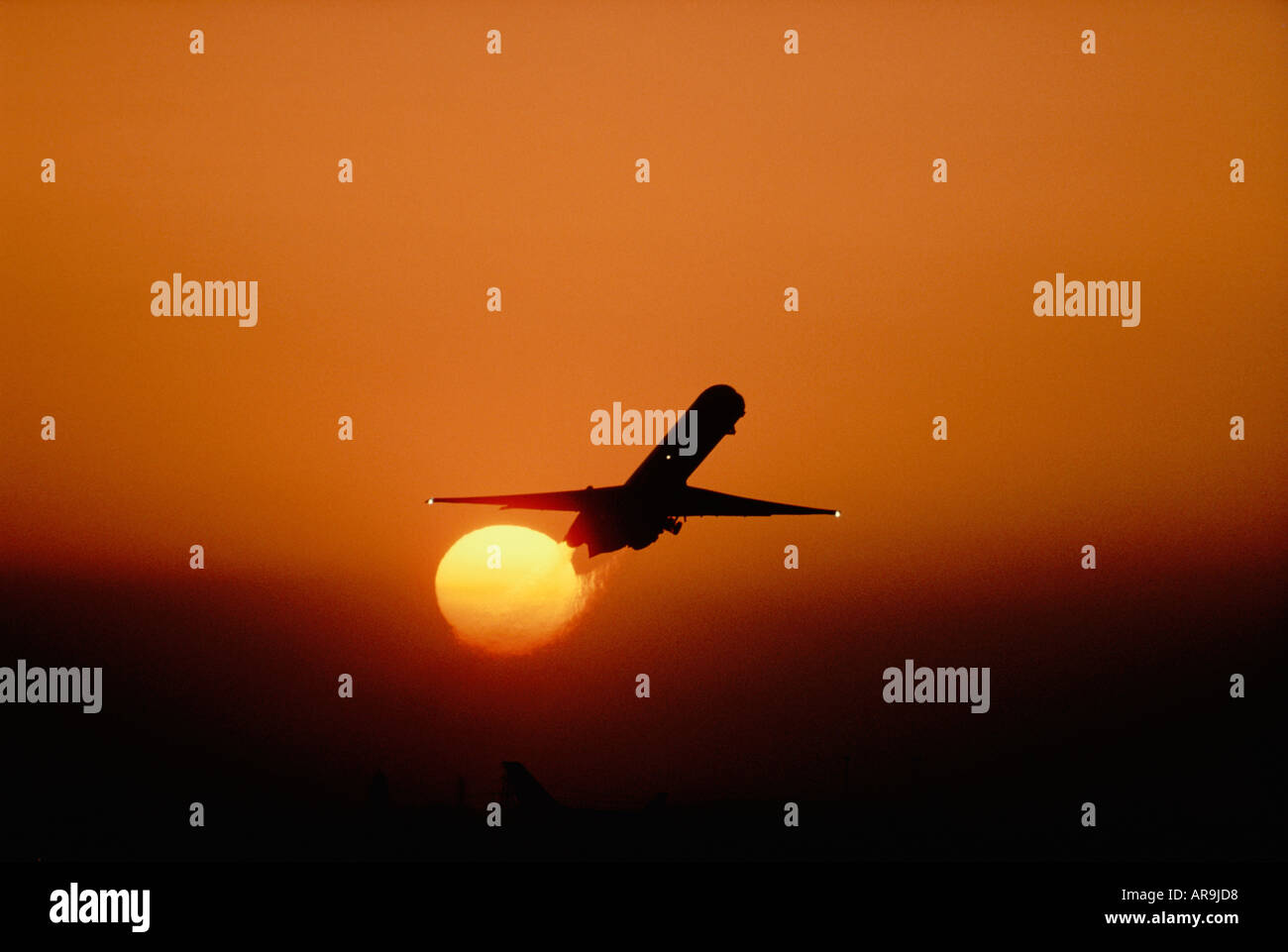 airliner jet in the air take off golden orange sky at sunset dusk showing jet thrust exhaust Stock Photo