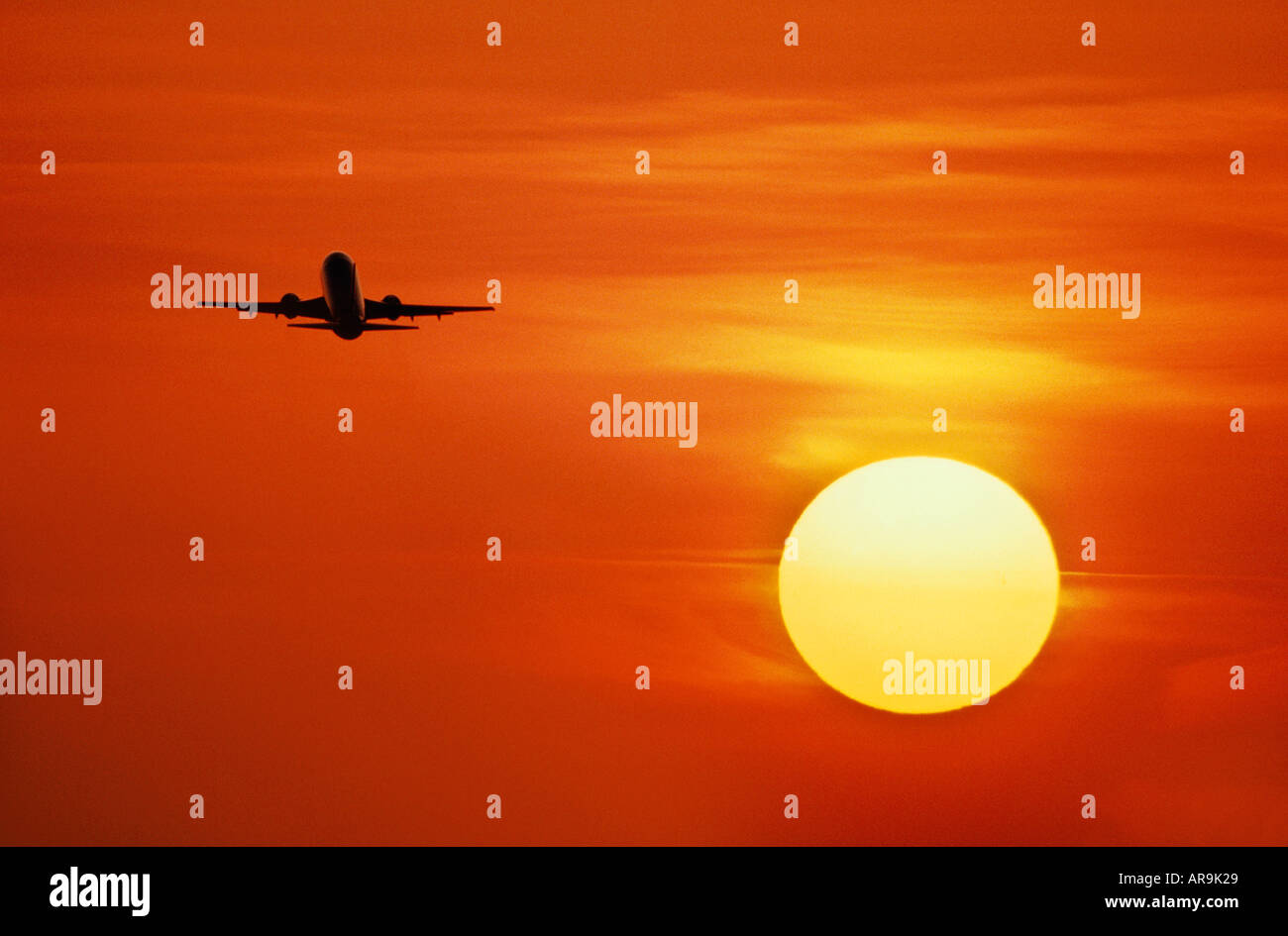 airliner Boeing 737 jet in the air on take off in an golden orange cloud sky at sunset sunrise dusk showing jet thrust exhaust Stock Photo