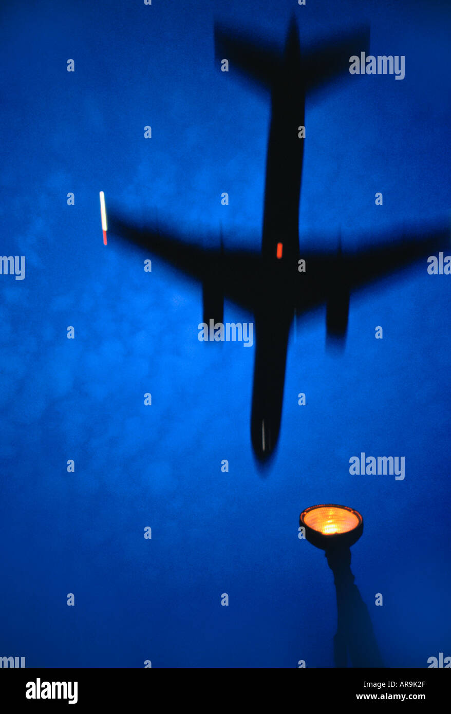 Boeing 757 jet airliner taking off flying over landing lights at dusk with a deep blue sky silhouette blurred movement Stock Photo