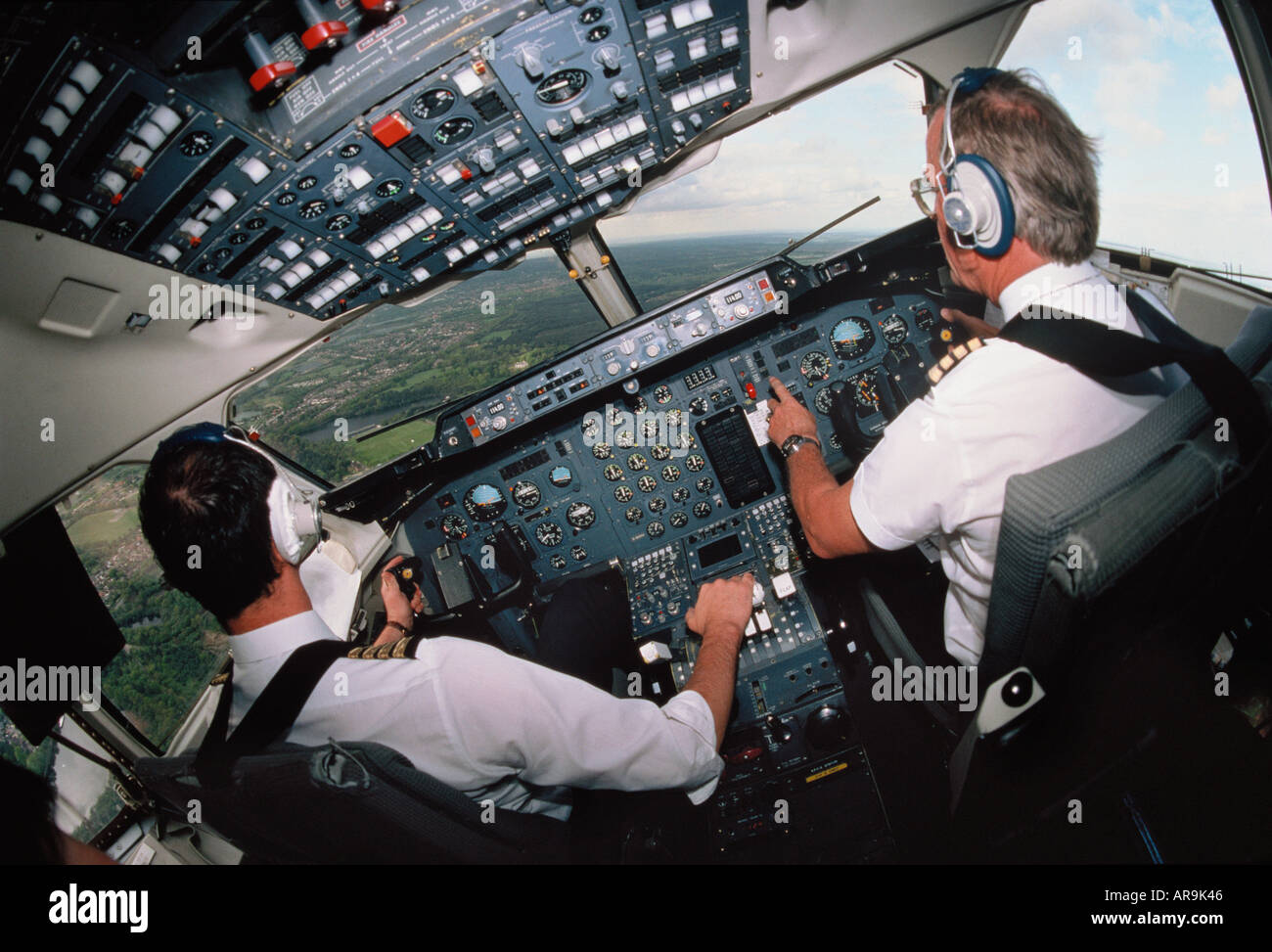 regional jet airliner pilots in cockpit at the avionics controls in a BAE 146 turning banking left with hand on throttles Stock Photo