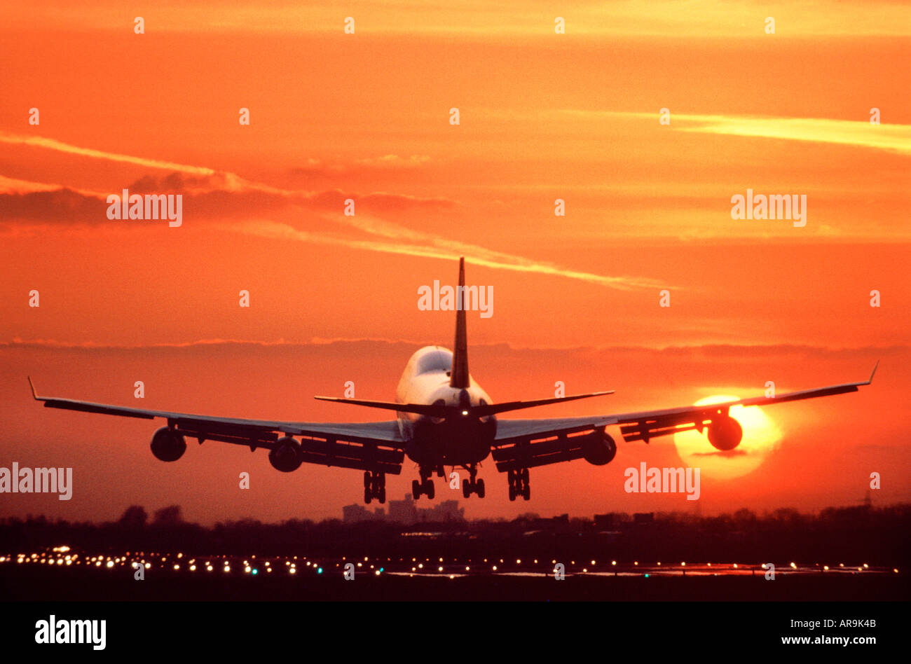 Boeing 747 jumbo jet airliner flying landing on a runway golden orange cloud sky at sunset with Windsor Castle behind Stock Photo