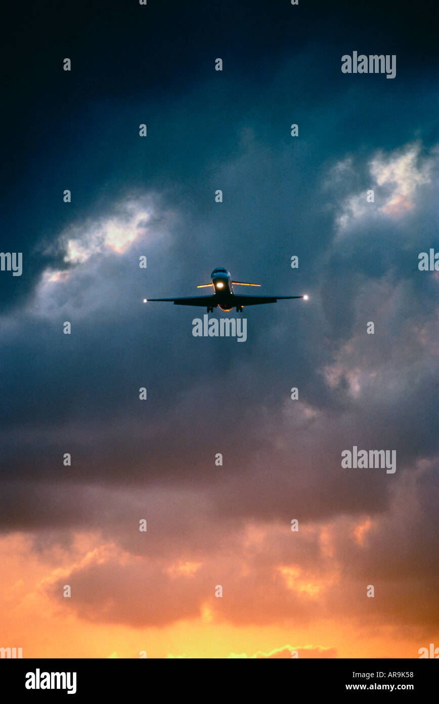 jet airliner with lights on approach to airport in a dark cloudy sky dusk Stock Photo