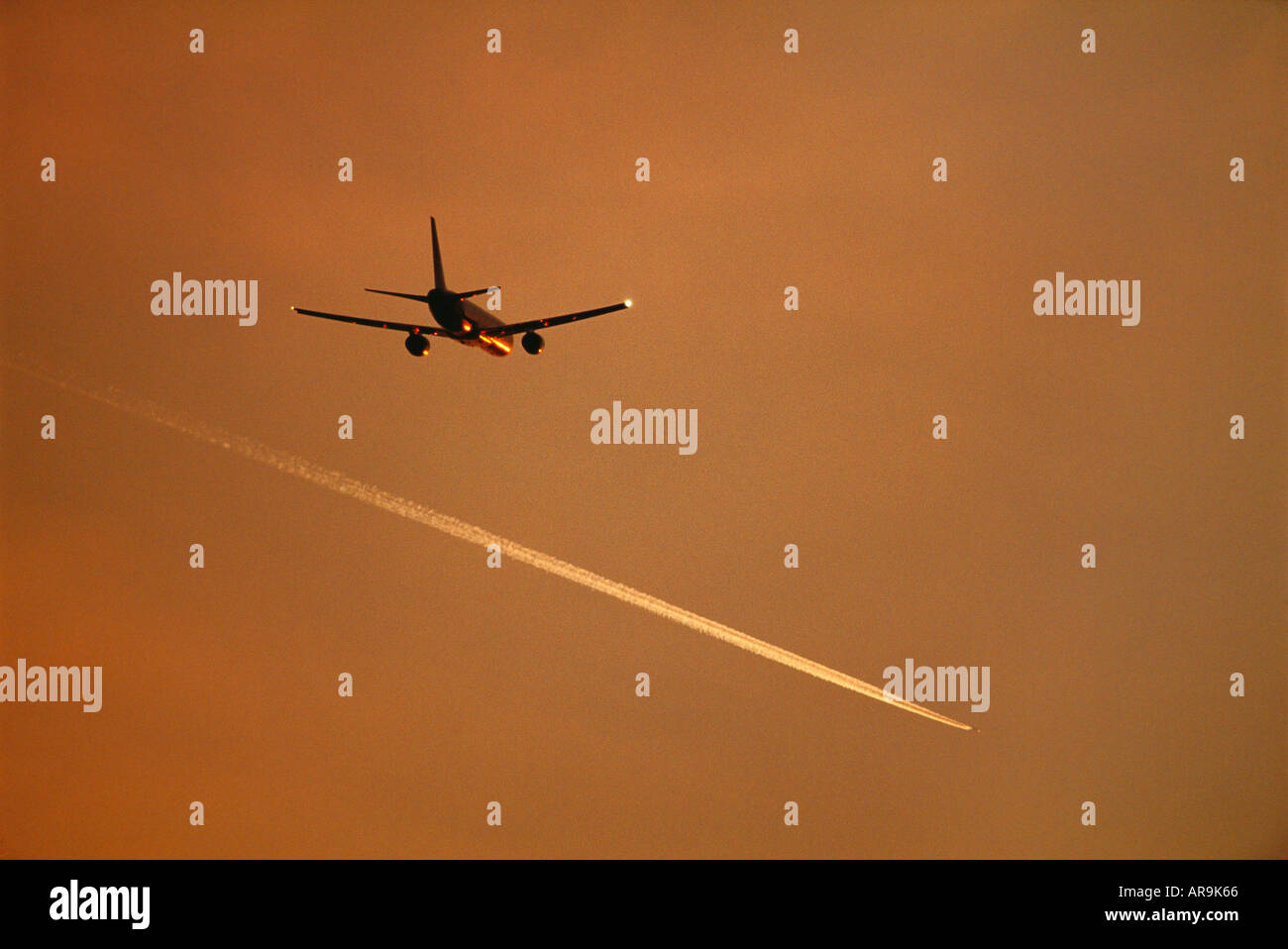 Boeing 757 jet airliner flying at cruising altitude and a contrail vapour trail at dusk sunset sunrise golden orange sky Stock Photo